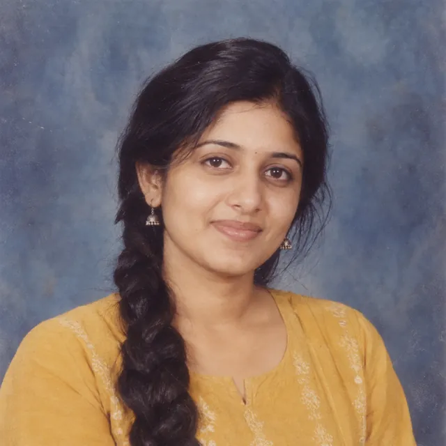 1990s yearbook-style portrait of a young Indian woman in a mustard kurta against a mottled blue-grey backdrop